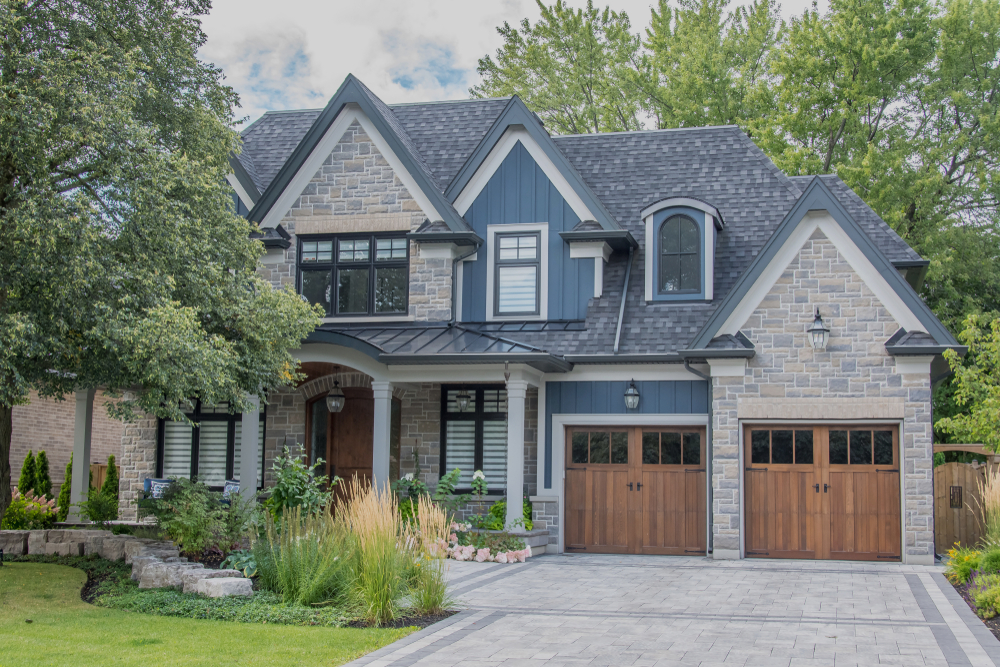a large, multi-level home with carriage-house style wood garage doors