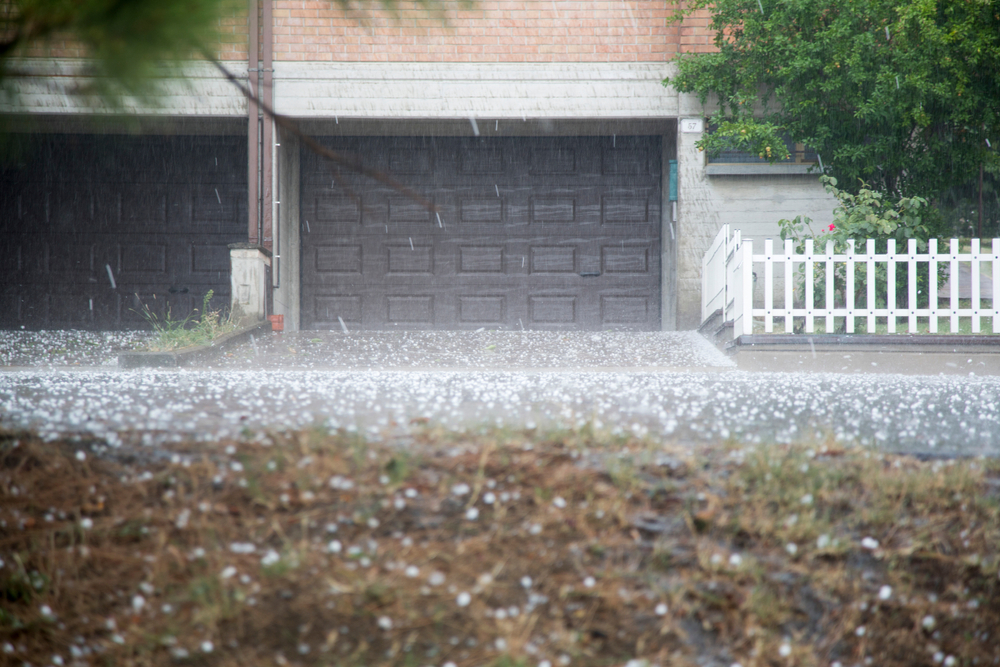 hailstones falling during a storm with a garage door in the background