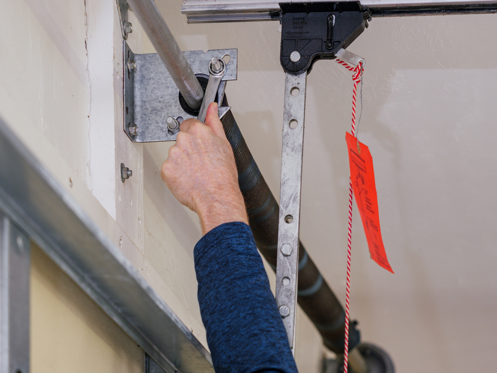 man repairing a broken garage door spring